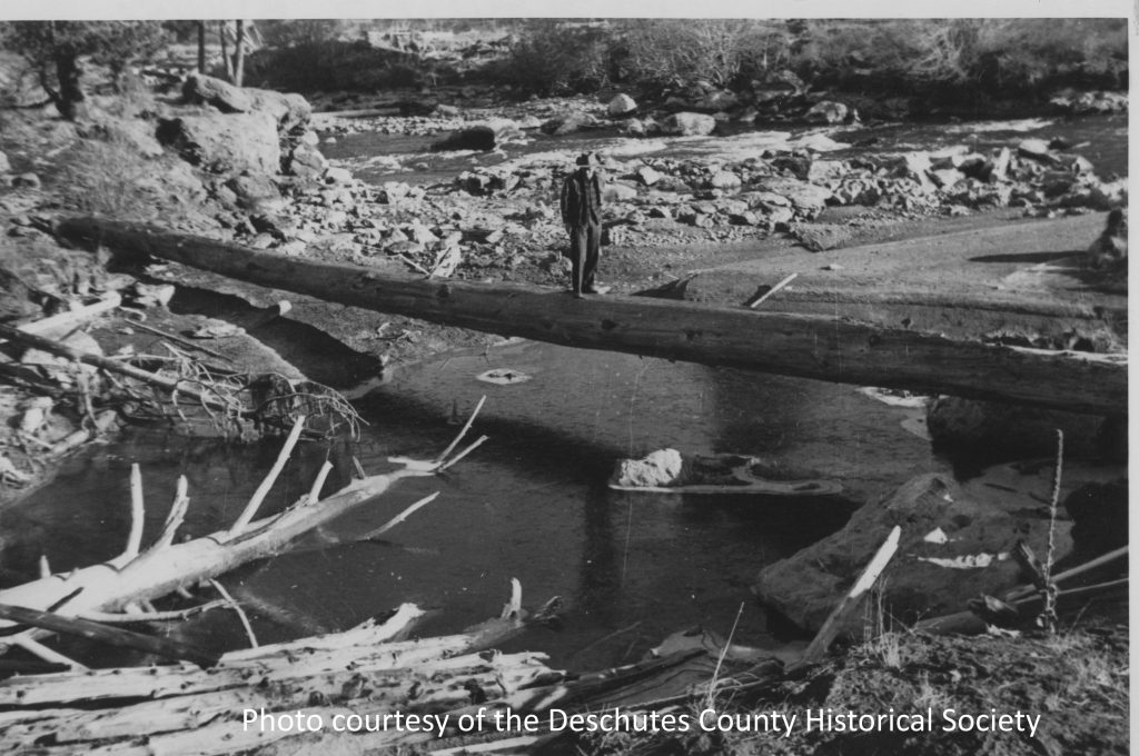 Man walking across river on log in 1947